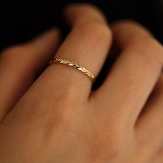 a woman's hand with a gold ring on top of her finger and an arrow shaped band