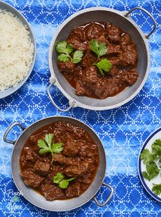 three pans filled with meat and rice on top of a blue table cloth