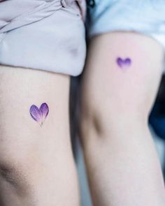 two women with tattoos on their legs, one has a heart shaped flower in the middle