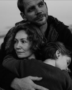 a black and white photo of a man holding a child with his arms around him