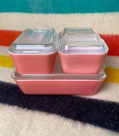 two glass containers sitting on top of each other in front of a colorful striped rug