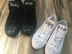 two pairs of white and black shoes with personalized names on the soles are sitting on a wood floor