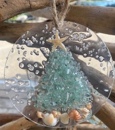 a glass ornament with a christmas tree and shells hanging from it's side