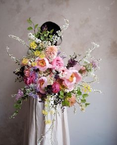 a woman holding a large bouquet of flowers in her hands and wearing a white dress