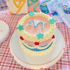 a birthday cake sitting on top of a white plate next to a red and white checkered table cloth