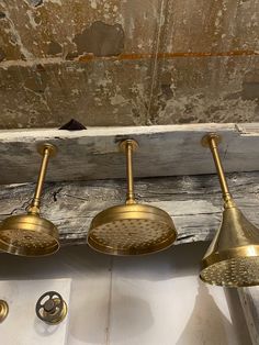 three brass shower heads are hanging from the ceiling