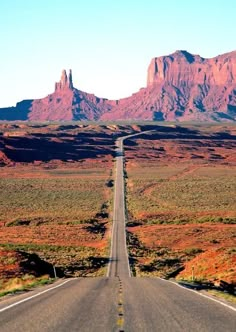 an empty road in the desert with mountains in the background