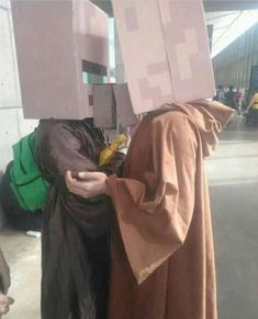 two people dressed in costumes standing next to each other with boxes on their heads,