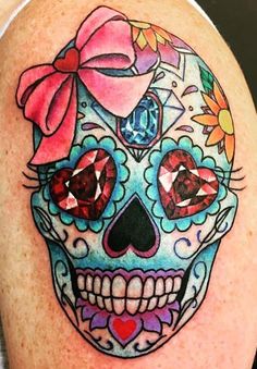 a colorful sugar skull tattoo on the back of a woman's shoulder and arm