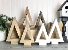 three wooden christmas trees sitting next to a birdhouse