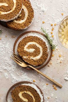 cinnamon roll with cream cheese frosting on two plates next to a glass of wine