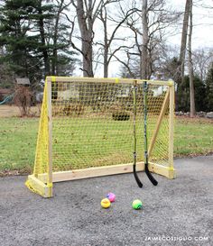 an outdoor soccer goal with three balls in front of it