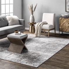 a living room with gray couches and white chairs in the corner, along with an area rug on the floor