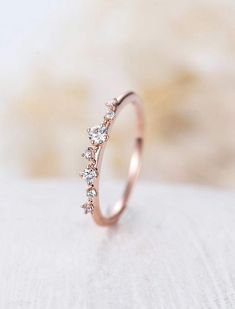 a rose gold ring with three small diamonds on the side, sitting on a white surface