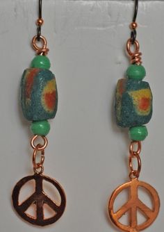 Green multicolored recycled glass beads are wire wrapped onto copper wire with a copper peace symbol.  Earrings hang approximately 2.5 inches from top of hypoallergenic niobium ear wires.  The focal recycled glass beads are made in Ghana, West Africa by a beading cooperative.    Item number: EA_028 Bohemian Green Dangle Beads, Peace Earrings Hippie, 925 Peace Sign Earrings, Adinkra Earrings, Symbol Earrings, African Earrings Handmade Afrikrea.com, Peace Earrings, Recycled Glass Bead, West Africa