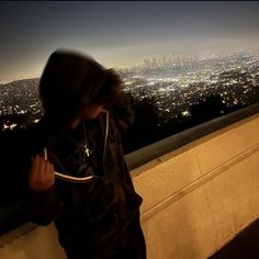 a person standing in front of a window with a view of the city at night