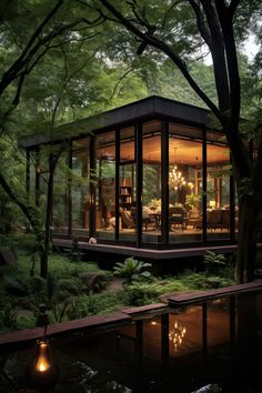 a glass house surrounded by trees and water