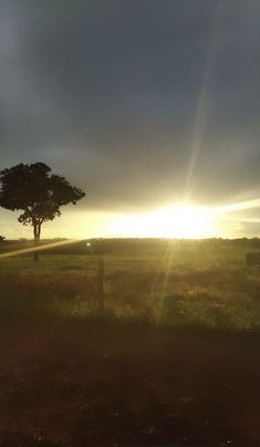 the sun is setting over an open field