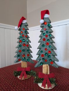 two wooden christmas trees with red and green bows on them sitting on a table next to each other