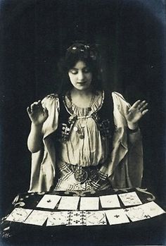 an old photo of a woman sitting at a table with cards in front of her