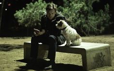 a man is sitting on a bench with his dog