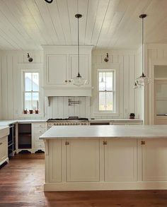 a large kitchen with white cabinets and wood flooring, along with an island in the middle