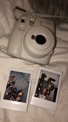 two polaroid cameras sitting on top of a bed next to pictures with the number five