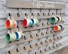 coffee cups are hanging on the wall with hooks