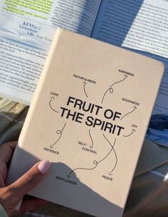 a person holding an open book with fruit of the spirit written on it in front of them