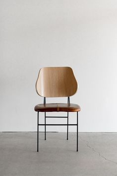 a wooden chair sitting on top of a cement floor next to a white wall in an empty room