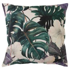 a green and white pillow with tropical leaves on the front, along with purple flowers