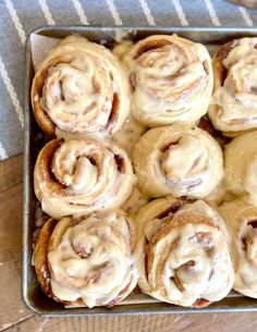 a pan filled with cinnamon rolls on top of a wooden table