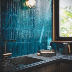 a kitchen sink under a window next to a blue tiled wall