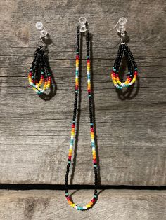 the multicolored beaded necklace and earring set is displayed on a wooden surface