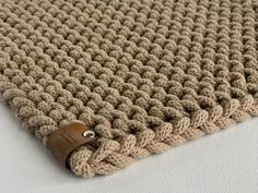 a close up of a knitted blanket with a leather tag on the bottom of it