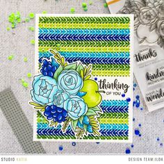 a card with blue flowers and green leaves on it, next to some crafting supplies