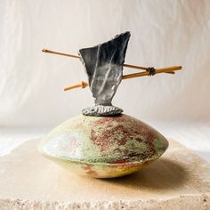 a stone sculpture with two sticks sticking out of it's back end and an object on top of it