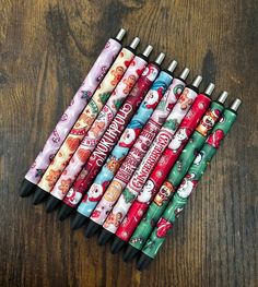 several pens are lined up next to each other on a wooden table with christmas themed items