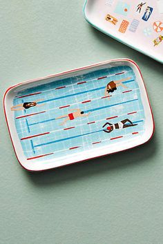 two trays with different designs on them, one is empty and the other has an image of people swimming