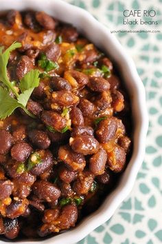 a white bowl filled with beans and cilantro on top of a green table cloth