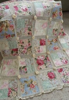 a crocheted blanket with roses on it is laying on the floor next to a chair