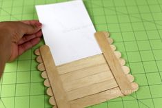 someone cutting out a piece of paper on top of a green cutting mat with scissors