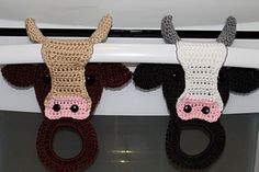 crocheted cow head hanging from the side of a refrigerator door handle with two rings