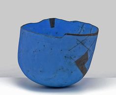 a blue bowl sitting on top of a white table next to a black and gray object