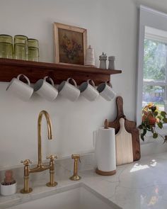 a kitchen with white walls and gold faucets on the shelf above the sink