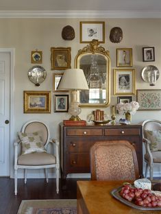 a living room filled with furniture and framed pictures on the wall above a wooden table