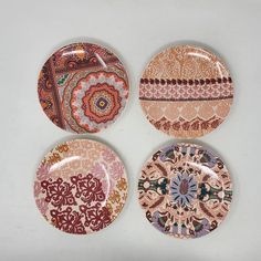 four plates with different designs on them sitting next to each other in a white surface