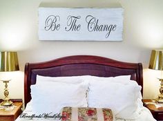 a bed with two lamps on either side and a sign above it that says be the change