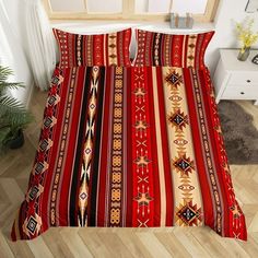 a bed with red and yellow striped comforter set on top of a wooden floor