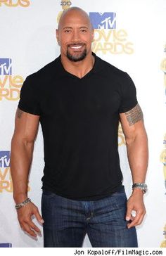 a bald man in black shirt and jeans posing for a photo on the red carpet